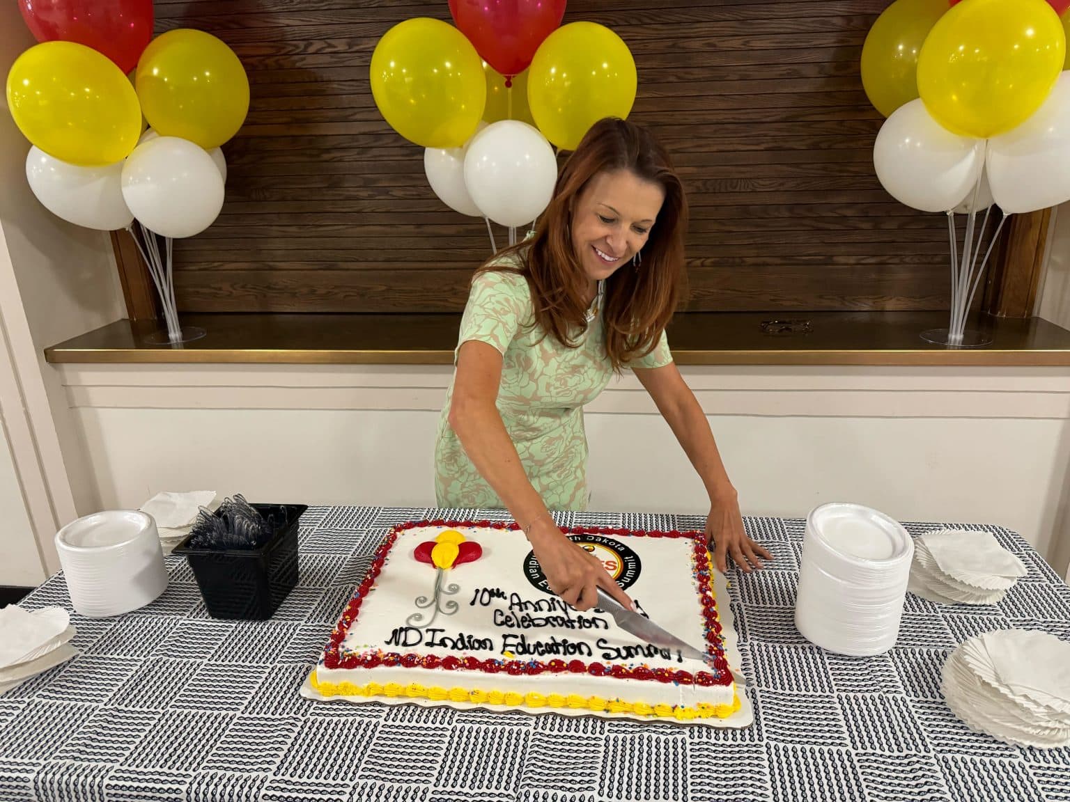 Since becoming North Dakota Superintendent of Public Instruction, Kirsten Baesler has been leading initiatives that have helped American Indian students succeed. Here she is pictured cutting a cake during the 10th annual Indian Education Summit at the state capitol in July 2024.