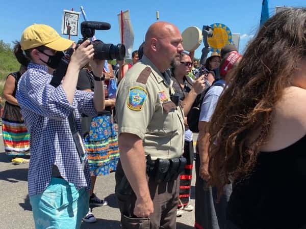 Clearwater County Sheriff Darin Halverson stands with water protectors listening to speakers during a June 7 march to the Mississippi River near an Enbridge Line 3 construction site. Halverson was able to avoid mass arrests that occurred at other protest sites near Solway, Minnesota. (Photo by Mary Annette Pember, Indian Country Today)
