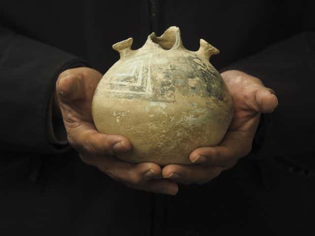 Eric Whyte, Hay Manager for the Ute Mountain Ute Farm & Ranch Enterprise near Towaoc, Colo., holds a pot that was used to hold water by the Anasazi People in the Four Corners area of Colorado thousands of years ago. The pot was found in a field when work began clearing land for the farm and ranch enterprise. Credit: Dean Krakel, special to Fresh Water News