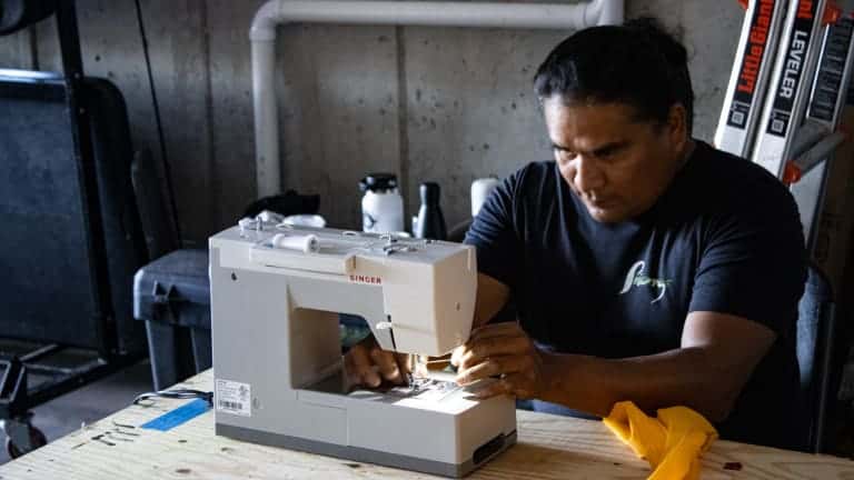 Cy Wagoner, Navajo and the creative resilience director for the NDN Collective, works on sewing a large banner for the Sept. 12 Washington D.C. protest for Leonard Peltier's freedom. (Photo by Amelia Schafer, ICT/Rapid City Journal)