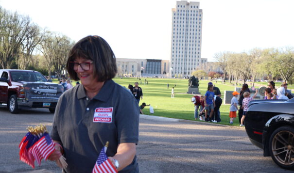 Rep. SuAnn Olson, R-Wilton, hands out flags May 10, 2024, during the Band Night parade in Bismarck. (Amy Dalrymple/North Dakota Monitor)