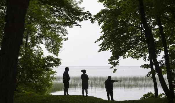 Mille Lacs Band of Ojibwe District 1 Representative Virgil Wind, Deanna Wilson Fredrickson and Commissioner of Natural Resources Kelly Applegate look out over Mille Lacs Lake from Band elder Dixie Kamimura’s home in Onamia, Minnesota on June 24. (Liam James Doyle for MPR News)