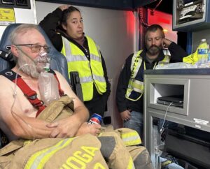 Tioga firefighter Jon Moberg receives oxygen while Cindy Hatch, a member of the Tioga EMS, and firefighter Joel Schaffett look on. Crews from Tioga were on hand to help locally with the fires while crews from outside facilities were on standby at the Tioga Medical Center. (Photo provided by Shelby Davis)